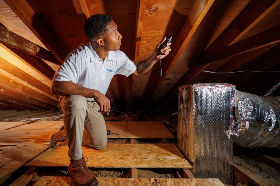 roofing engineer squatting in the attic looking at rafters