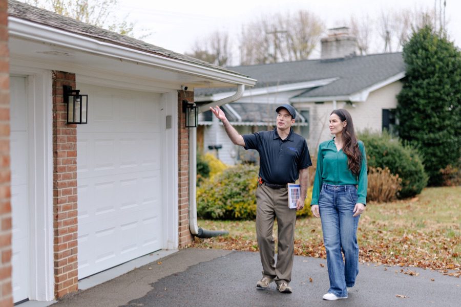 roofing engineer pointing at roof and talking with woman homeowner